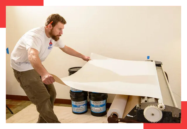 Wallpaper hanger applying paste to wallpaper